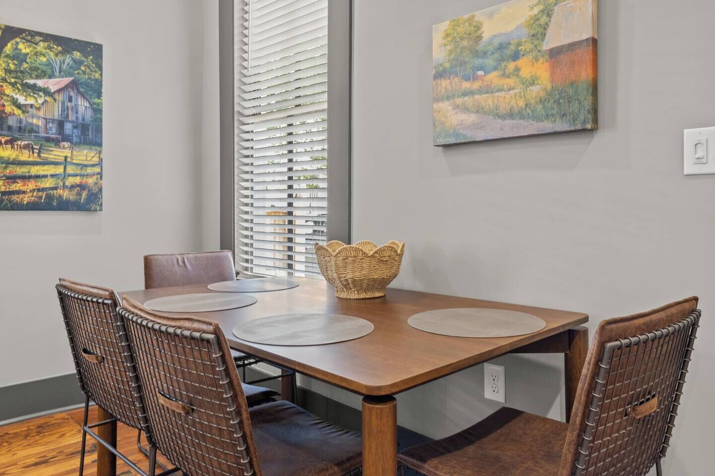 Un comedor con una mesa de madera, sillas de mimbre y una cesta.