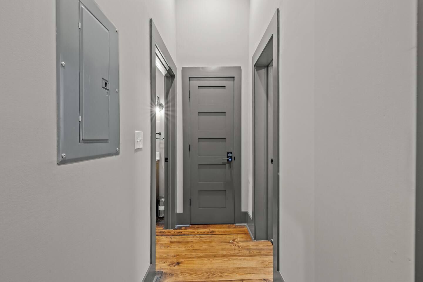 Un couloir étroit, doté d’un plancher en bois et de portes grises de part et d’autre.