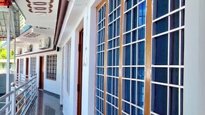 A corridor with large windows and a ceiling with circular patterns. - Geetanjali Palace  (Jakholi)