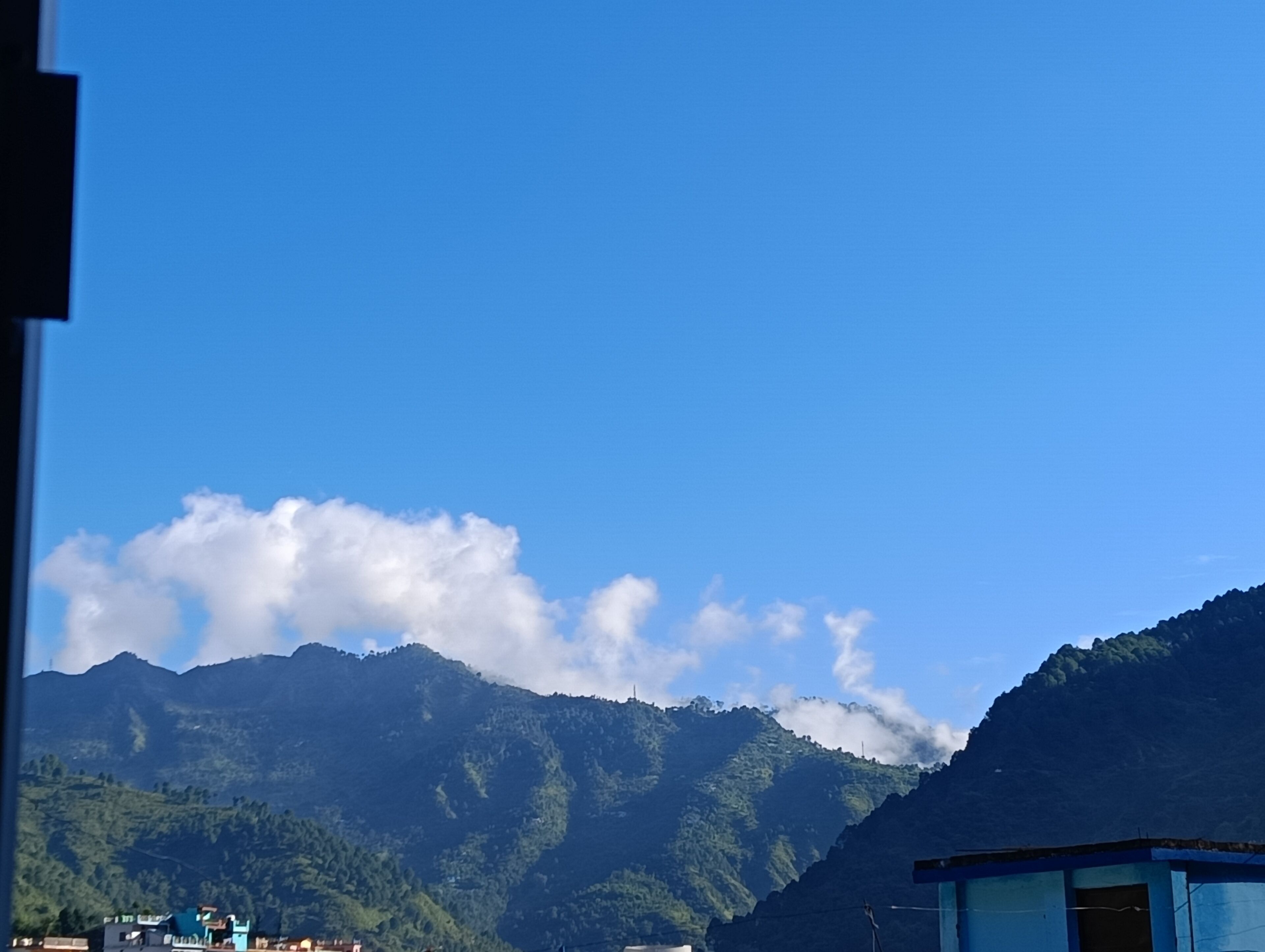 Paisatge de muntanyes sota un cel clar i algunes boires.