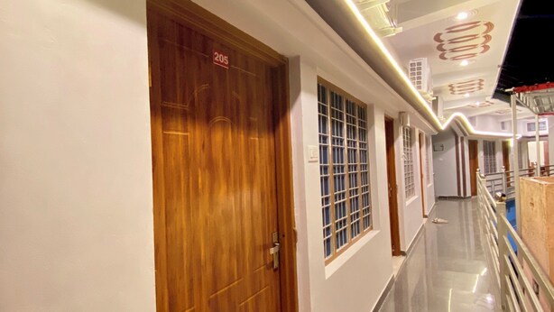 A corridor with a wooden door labeled '205', a polished floor, and a ceiling with decorative lighting fixtures. - Geetanjali Palace  (Jakholi)
