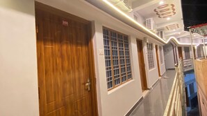 A corridor with wooden doors, air conditioning units, and a ceiling with circular patterns. - Geetanjali Palace  (Jakholi)