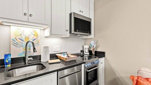 A modern kitchen with white cabinets, stainless steel appliances, a microwave, and a coffee maker.