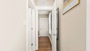 A hallway with white doors, a framed picture on the wall, and a wooden floor.