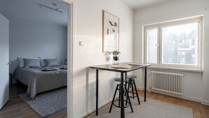 Un dormitorio con cama, mesita de noche y ventana.