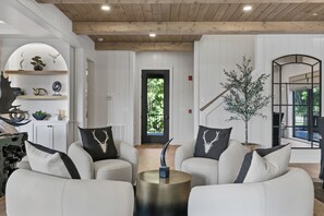 A modern living room with white sofas, a round metallic coffee table, and a potted plant.