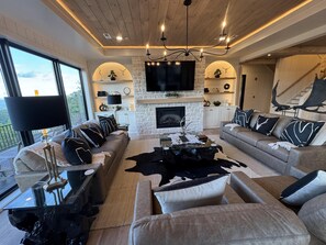 A modern living room with a fireplace, sofas, a coffee table, and a TV mounted on the wall.