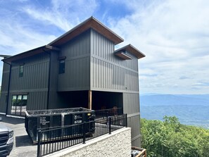 Ein modernes, zweistöckiges GebĂ€ude mit Balkon, MĂŒlleimer und Blick auf ferne Berge.