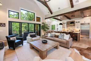 A spacious living area with a large window, a dining area, and a kitchen with modern appliances.