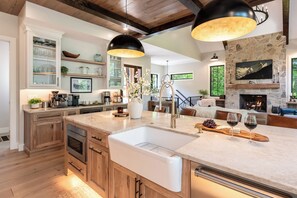 A modern kitchen with a central island, built-in appliances, and a stone fireplace.