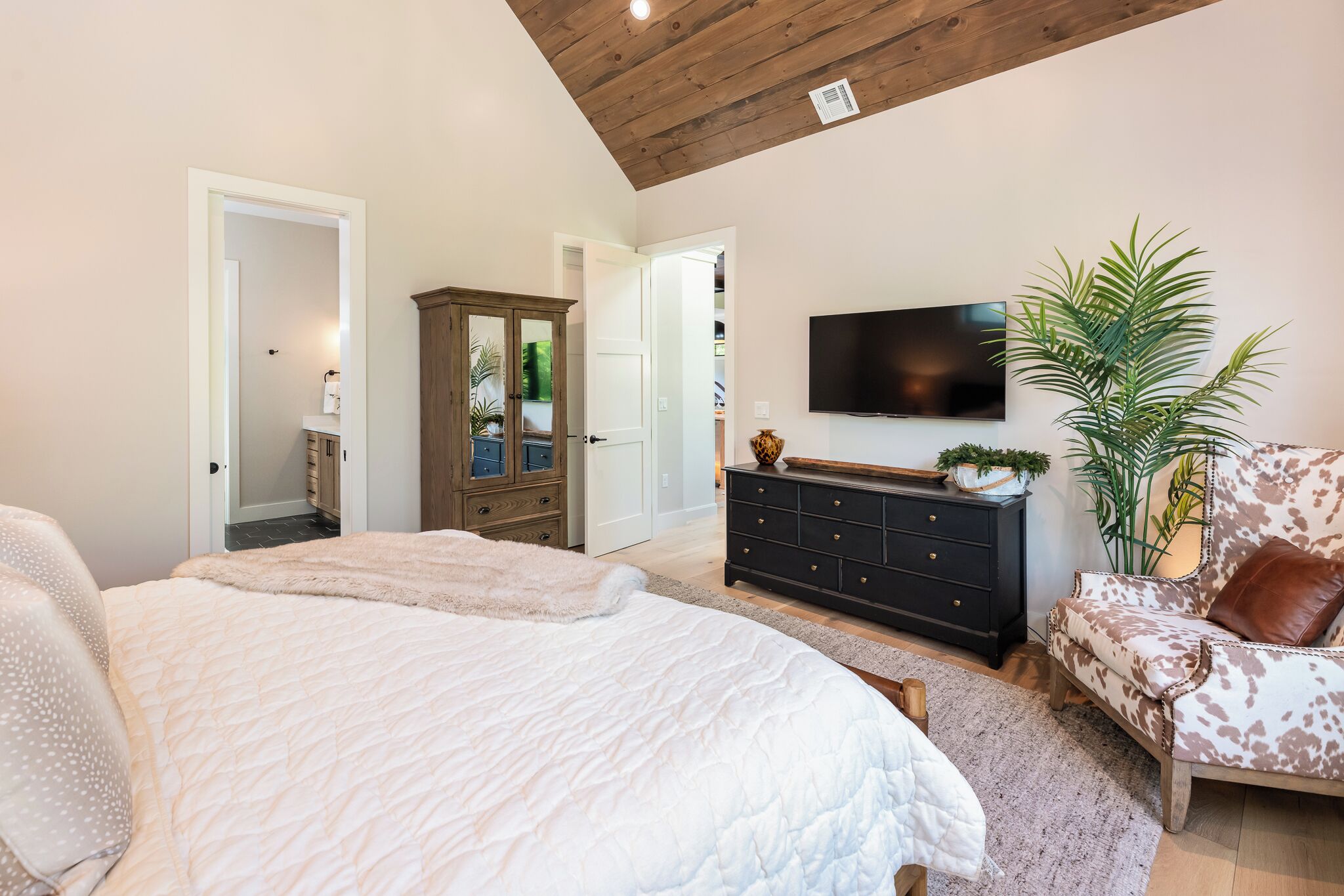 A bedroom with a large bed, a dresser, a TV, and a sofa.