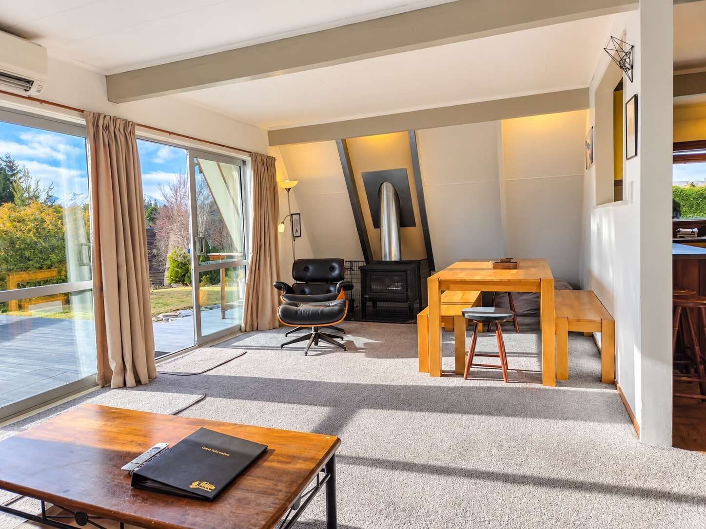 A modern interior with a dining area, a fireplace, and a large window offering a view of the outdoors.