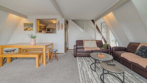 Un apartamento loft moderno con comedor, dos sofás, una mesa de centro y vistas a la ciudad.
