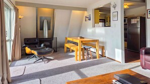 Un espacio habitable compacto con sofá, mesa de comedor, zona de cocina y chimenea.