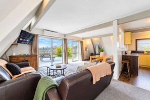 Een moderne woonkamer met een bank, een salontafel en een eethoek met uitzicht op de omgeving.