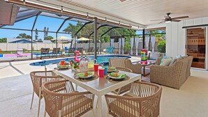 An outdoor patio with a pool, wicker furniture, and ceiling fans.