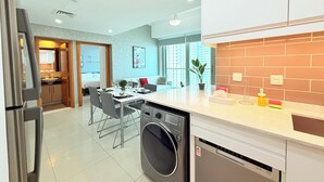 Una cucina moderna con lavatrice, un'area pranzo con tavolo e sedie, e vista sulla città attraverso ampie finestre.
