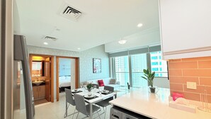 Una cucina moderna con lavatrice e asciugatrice integrate, un'area pranzo con tavolo e sedie, e vista sulla città attraverso ampie finestre.