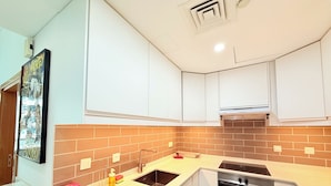 Una cucina moderna con mobili bianchi, forno in acciaio inossidabile e parete di fondo rivestita di piastrelle.