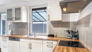A modern kitchen with white cabinets, a stainless steel sink, a built-in oven, and a coffee maker. - Holiday Home 'Fewo Neubörger Wellness' with Private Pool, Wi-Fi and Air Conditioning (Neubörger)