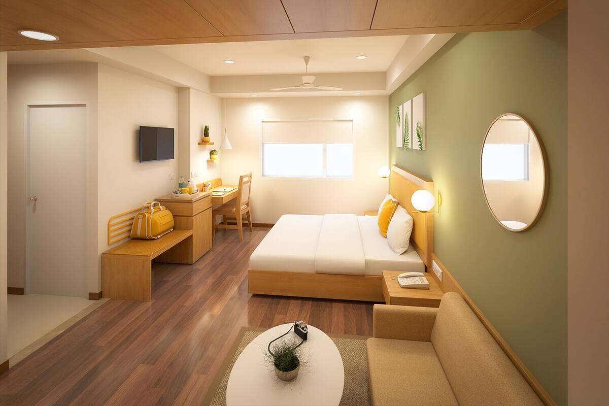 Una habitación de hotel moderna con cama, escritorio, sofá y una pequeña mesa con una planta.