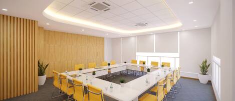 A conference room with a long table, yellow chairs, potted plants, and a wooden panel wall.