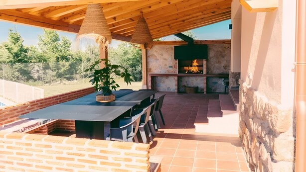An outdoor patio with a brick wall, wooden ceiling, and a grill area. - Country House in Torrecaballeros with Mountain Views, Private Pool, and Wi-Fi (Torrecaballeros)