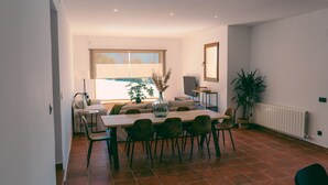 A dining area with a table and chairs, a sofa, a radiator, and a window with blinds. - Country House in Torrecaballeros with Mountain Views, Private Pool, and Wi-Fi (Torrecaballeros)