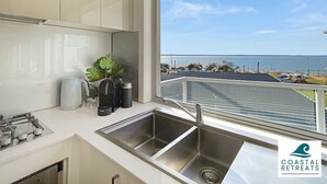 A modern kitchen with a large window overlooking a coastal view, including a marina and the sea. - Hamptons Retreat by the Bay - Cowes Coastal Escape (Cowes)