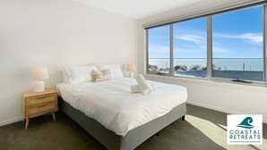 A bedroom with a large window, a bed, a nightstand, and a lamp. - Hamptons Retreat by the Bay - Cowes Coastal Escape (Cowes)