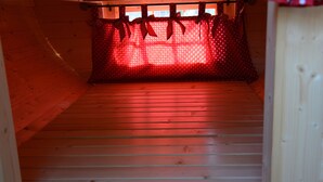 Interior de madera con una cortina roja y lazos, suelo de madera y una ventana con vistas.