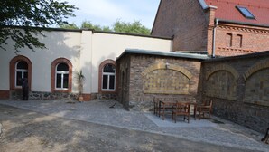 Un patio con un muro de ladrillo, un muro de piedra y un edificio con ventanas de arco.