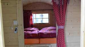Una habitación pequeña y acogedora con una cama nido, una escalera y una ventana con cortinas.