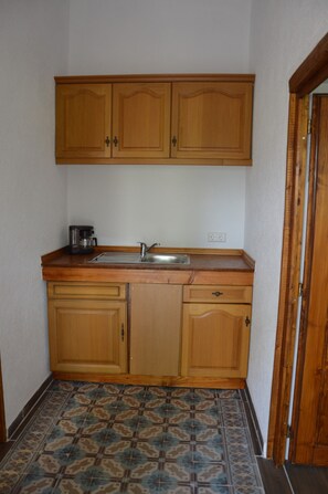 A small kitchen with wooden cabinets, a sink, and a coffee maker.