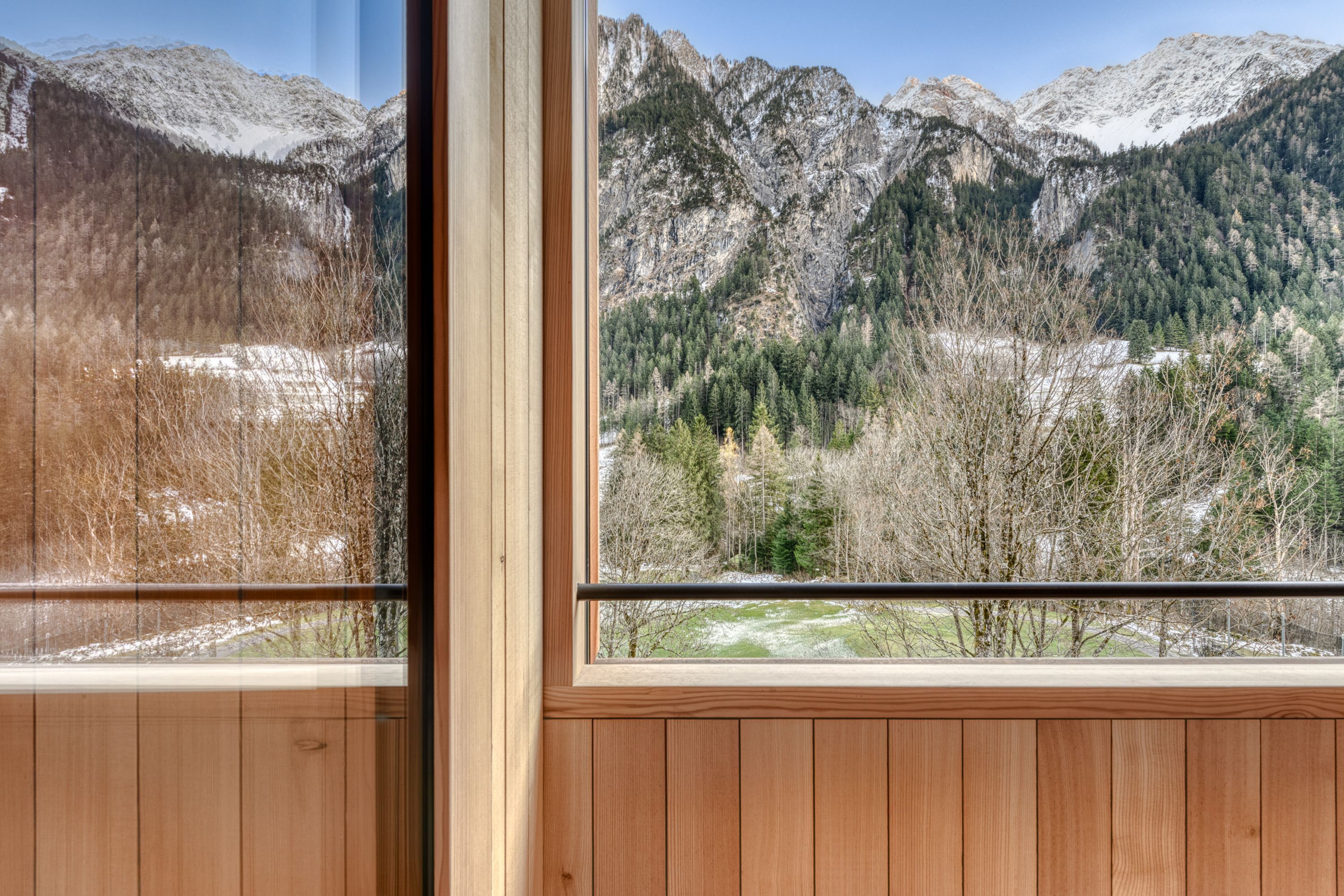 A room with wooden paneling and a large window offering a view of snow-covered mountains and trees.