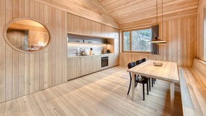 Eine moderne Küche mit Holzvertäfelung, einem runden Spiegel und einem Essbereich mit Tisch und Stühlen.