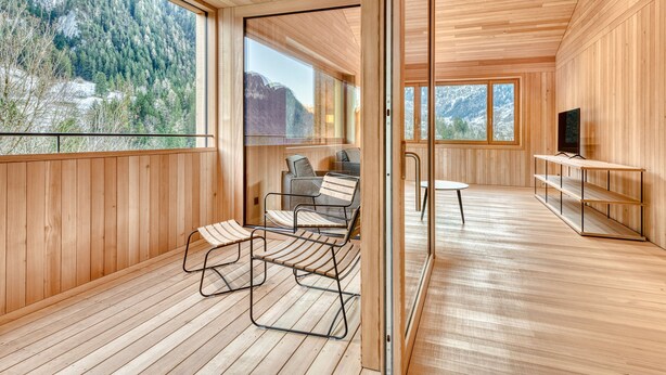 Ein Holzinterieur mit großen Fenstern, einem Fernseher und einem Tisch.