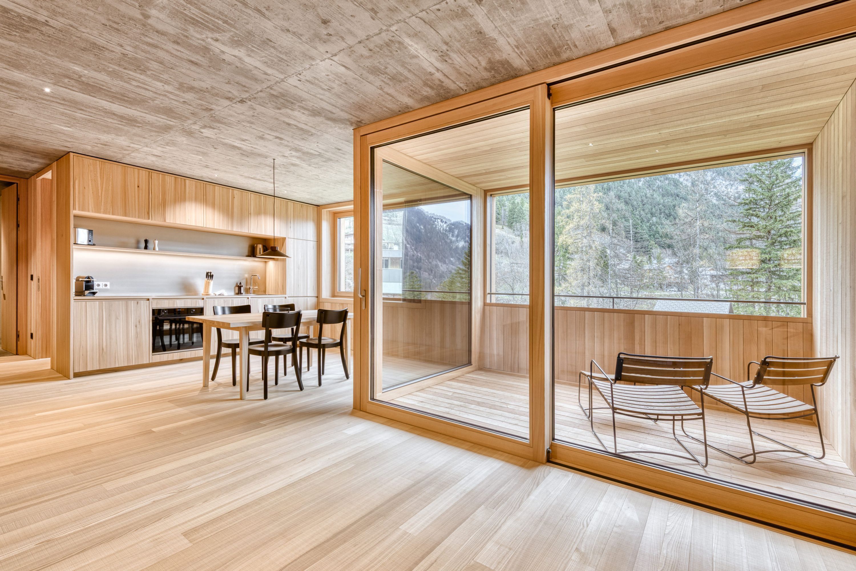 A modern kitchen with wooden cabinets and a dining area with a table and chairs.