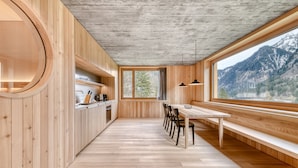 A modern kitchen with wooden cabinetry, a central island, and a large window overlooking a mountainous landscape. - Studa 29 - Studa 6 in Brand (Brand)