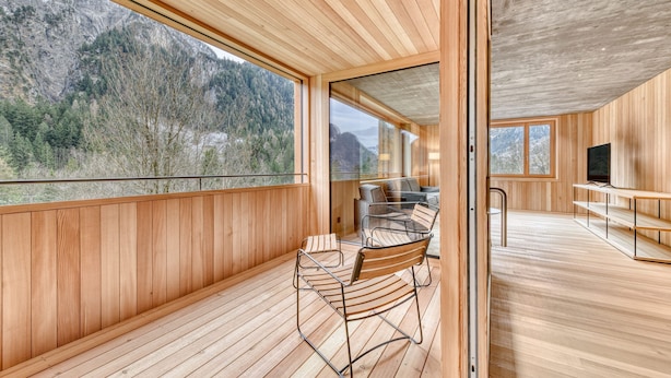 A modern interior with wooden paneling, a dining area with metal chairs, and large windows offering mountain views. - Studa 29 - Studa 6 in Brand (Brand)