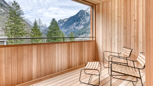 A balcony with wooden walls and a view of mountains. There are two metal chairs and a bench. - Studa 29 - Studa 1 in Brand (Brand)