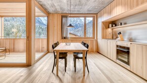 Eine moderne Küche mit Holzschränken, einem großen Esstisch und Bergblick durch die Fenster.