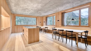 Une cuisine moderne avec des meubles en bois, un îlot central et un coin repas comprenant des chaises et une longue table.
