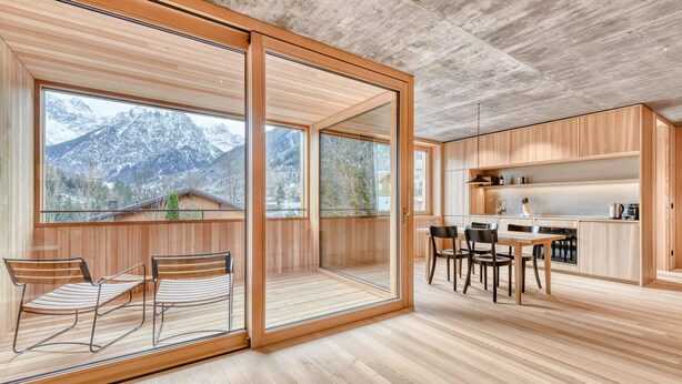 A modern kitchen with wooden cabinets and a dining area with chairs and a table. - Studa 29 - Studa 7 in Brand (Brand)