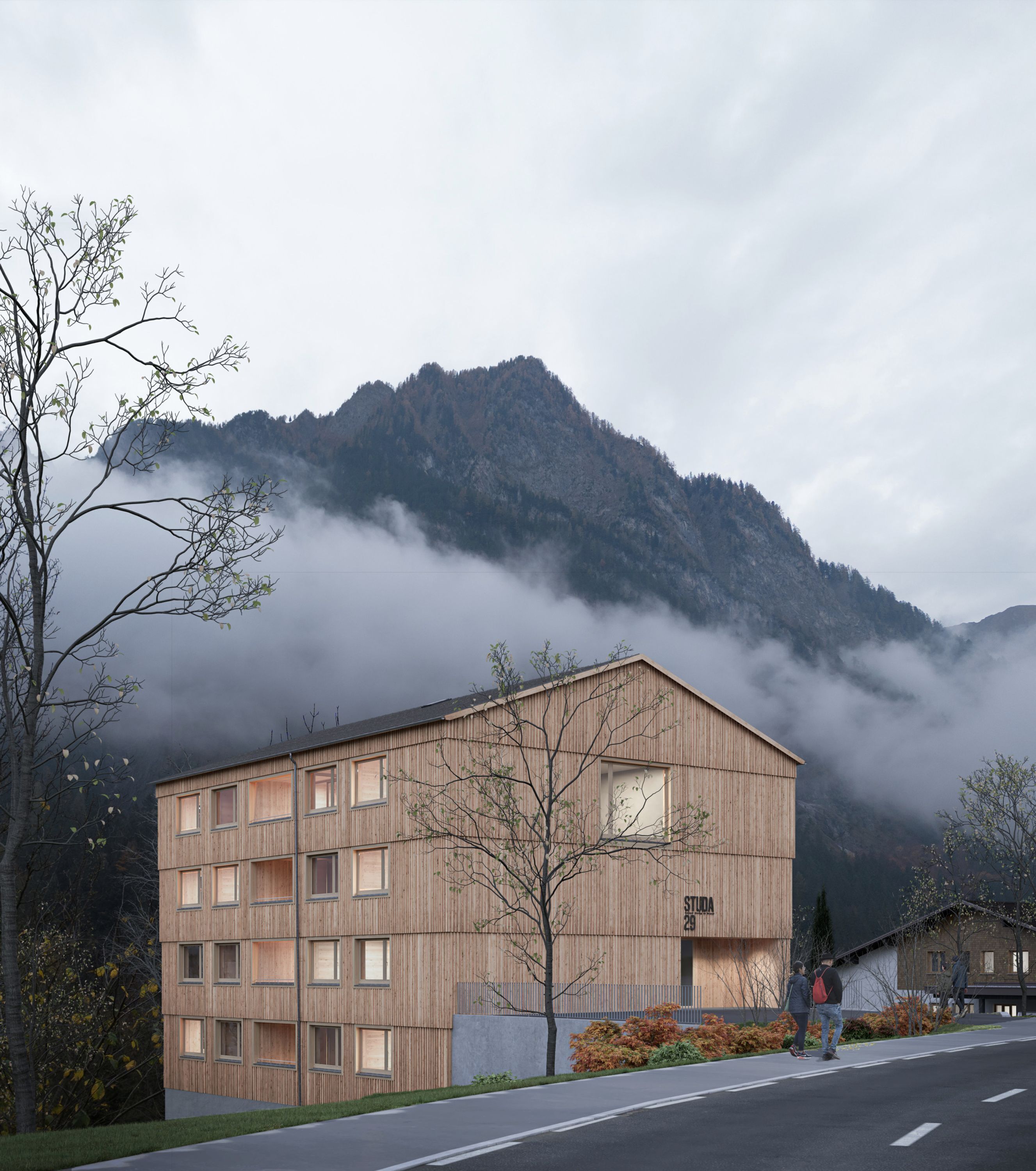 A modern wooden building with multiple windows, situated in a mountainous area with a road in the foreground and a person standing near the entrance.