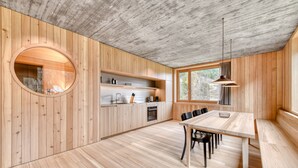 A modern kitchen with wooden cabinetry, a round window, and a dining area with a bench and chairs. - Studa 29 - Studa 2 in Brand (Brand)