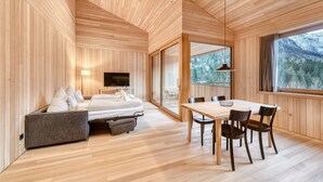 A modern room with wooden walls and floors, a bed, a dining table with chairs, and a large window with a mountain view. - Studa 29 - Studa 10 in Brand (Brand)