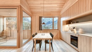 A modern kitchen with wooden cabinets, a large dining table, and a view of mountains through the window. - Studa 29 - Studa 10 in Brand (Brand)