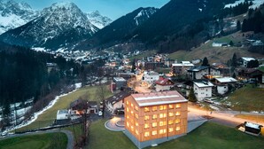 A modern building with multiple windows and a flat roof, surrounded by a small town with houses and a mountain in the background. - Studa 29 - Studa 10 in Brand (Brand)