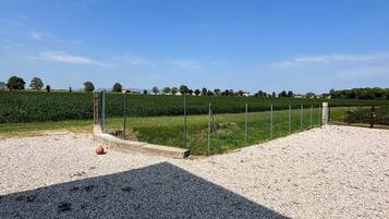A gravel parking area with a fence and a field in the background.